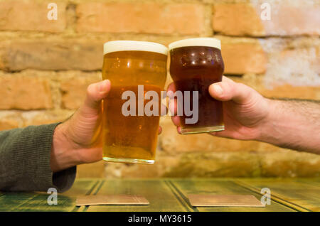 Freunde an der Bar Tisch halten zwei Pints Bier, Prost Stockfoto