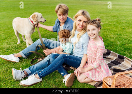 Glückliche junge Familie mit Golden Retriever Hund sitzen auf Plaid im Picnic Stockfoto