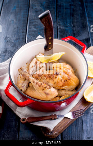 Einen gusseisernen Topf und ein goldenes Huhn mit Zitrone und Rosmarin aus dem Ofen. Köstliches Abendessen mit der Familie. Für Text setzen. Kopieren Sie Platz Stockfoto