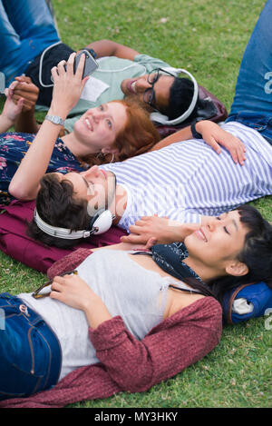 Eine Gruppe von Freunden, die auf Gras zusammen entspannen Stockfoto