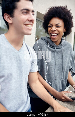 Freunde hören, Kopfhörer und zusammen lachen Stockfoto