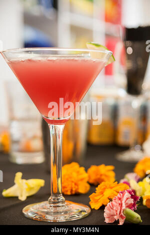 Erfrischende Frucht Cocktail in einem Martini Glas mit Nelke Blume serviert Akzente auf dem Display für Gäste auf einer Party. Stockfoto