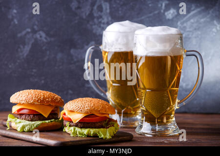 Foto von zwei Hamburger, Gläser mit Bier Stockfoto