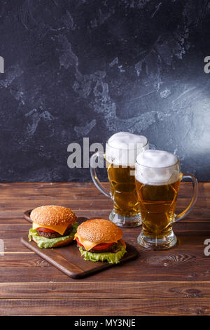 Foto von zwei Hamburger, Gläser mit Bier Stockfoto