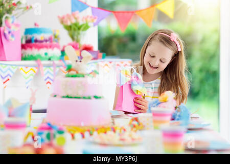 Kindergeburtstag mit bunten Rainbow pastell Dekoration und Bunny Layer Cake. Kleines Mädchen mit Süßigkeiten, Süßigkeiten und Obst. Ballons und Banner bei Fes Stockfoto