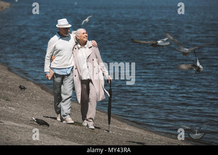 Gerne älteres Paar umarmen im Quay und fliegende Vögel Stockfoto