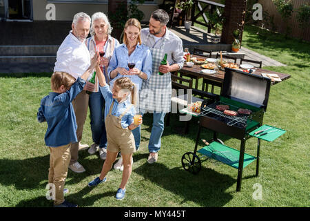 Mädchen, fünf zu Bruder mit in der Nähe von lächelnden Familie stehen am Grill Stockfoto