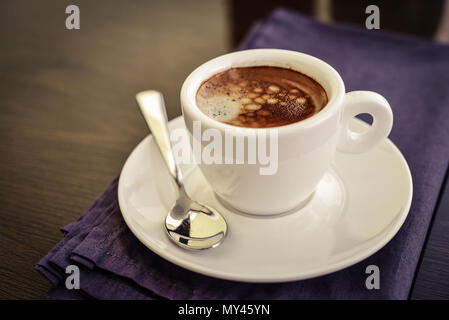 Espresso in der kleinen weißen Schale mit einem Löffel ruht auf dem Holz Hintergrund Stockfoto