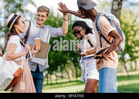 Fröhlicher junger multiethnischen Studenten hoch fünf beim zusammen in PARK-Stellung Stockfoto