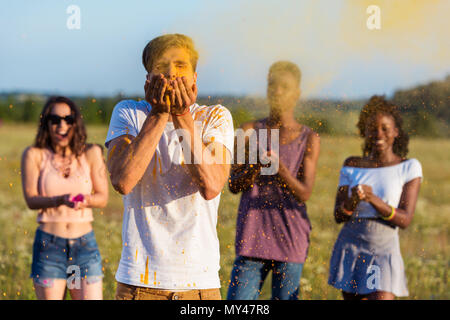 Jungen multiethnischen Freunde blasen Pulver aus Palmen im Holi Festival Stockfoto