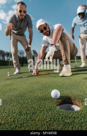 Young Professional Golf Spieler, die am Ball in der Nähe der Bohrung Stockfoto