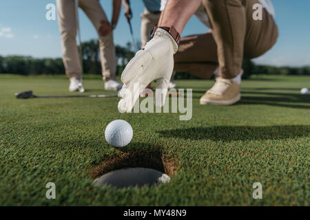 7/8 shot Golf Player im Handschuh, Ball in der Nähe der Bohrung zu erhalten Stockfoto