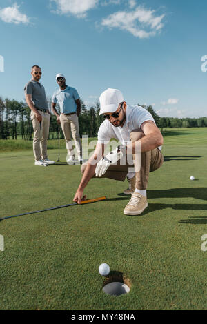 Professional Golf Spieler am Ball in der Nähe der Bohrung am Tag suchen Stockfoto