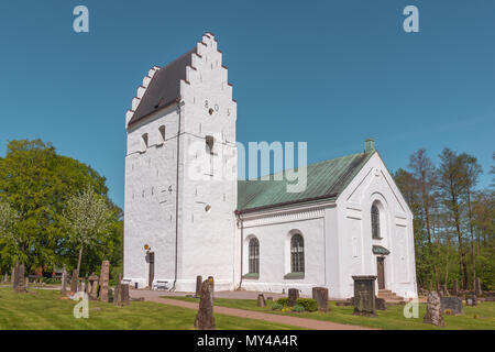 Eine weiße skandinavischen mittelalterliche Kirche mit der abgestuften Giebel und Grabsteine auf dem grünen Rasen, Finja, Schweden, 9. Mai 2018 Stockfoto