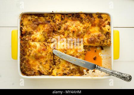 Hausgemachte Lasagne Bolognese mit mit Messer auf weissem Holztisch Stockfoto