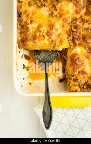 Hausgemachte Lasagne Bolognese mit Rindfleisch, Sauce Bolognese und Basilikum auf weissem Holztisch Stockfoto