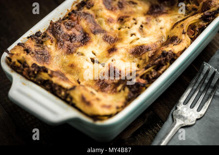 Lasagne mit Hackfleisch, Sauce Bolognese und Mozzarella auf dunklem Hintergrund. Im rustikalen Stil. Stockfoto