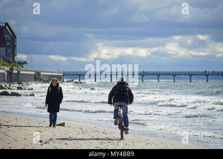 Zelenogradsk, Russland - 17. Mai 2016: Eine ältere Frau Spaziergänge entlang der sandigen Strand in Richtung der Radfahrer. Stockfoto