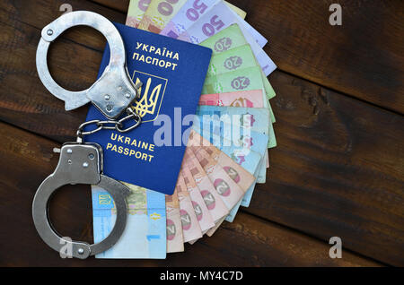 Ein Foto von einem ukrainischen ausländischer Reisepass, eine bestimmte Menge von ukrainischen Geld und Polizei Handschellen. Das Konzept der Verhaftung von Ukrainischen illegalen imm Stockfoto