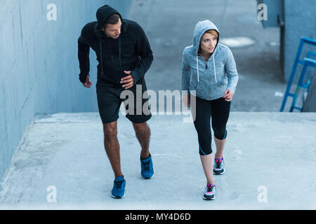 Athletische Sportlerin und Sportler joggen auf Treppen in Stadt Stockfoto