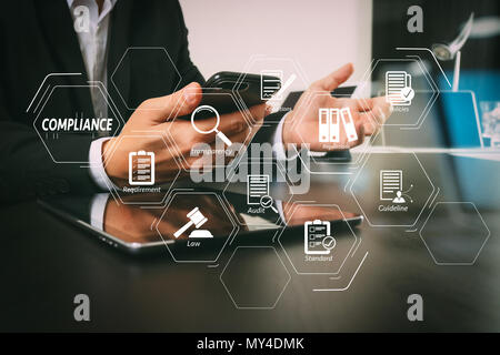 Einhaltung der Virtuellen Schaltplan für Verordnungen, Gesetze, Normen, Anforderungen und Prüfung. Geschäftsmann arbeiten mit Smart Phone und digitale Tablet-PC und Laptop Stockfoto