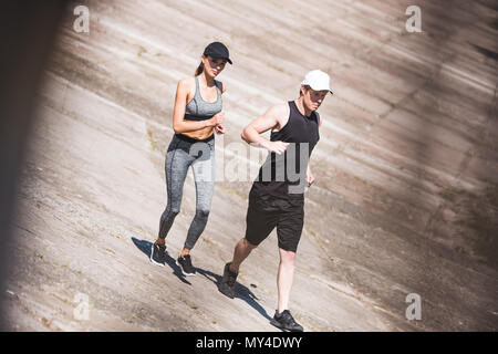 Junge sportliche Paar joggen gemeinsam auf Steinplatten Stockfoto