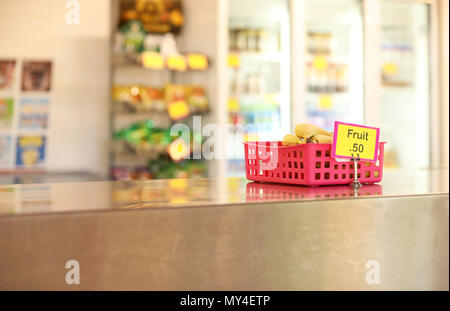 Schulkantine tuck Shop eine Cafeteria, gesundes Obst essen Optionen für Studenten. Bananen in einer roten Fach auf Edelstahl Tisch im Vordergrund Stockfoto