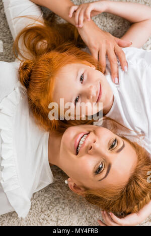 Ansicht von oben der lächelnden Mutter und Tochter gemeinsam auf dem Boden liegend zu Hause Stockfoto