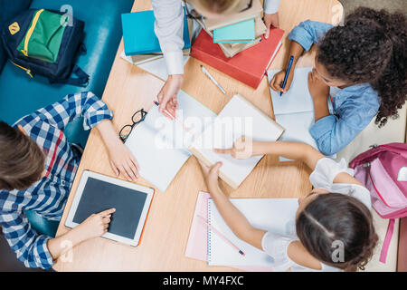Blick von oben auf die Lehrer und Schüler Hausaufgaben zusammen Stockfoto