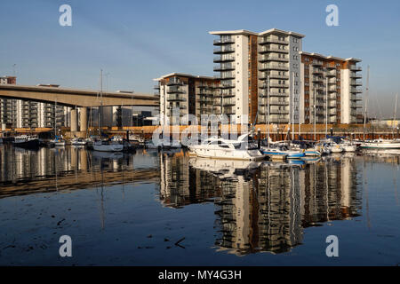 River Ely in Cardiff Bay Wales, Großbritannien, mit modernen Apartments am Fluss Reflections im Wasser, Booten auf Fluss moderne Wohnturm-Architektur Stockfoto