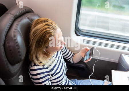 Frau Kommunikation über Mobiltelefon während der mit dem Zug reist. Stockfoto