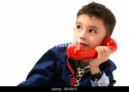 Studio shot der netten Jungen sprechen auf alten Telefon beim Denken Stockfoto