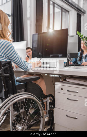 7/8 Bild der Frau im Rollstuhl mit Grafiktablett im modernen Büro Stockfoto