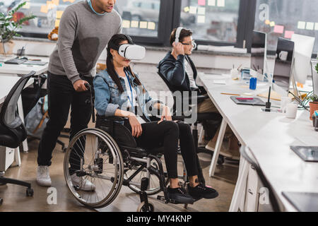 Frau im Rollstuhl mit Virtual reality Brillen im modernen Büro Stockfoto