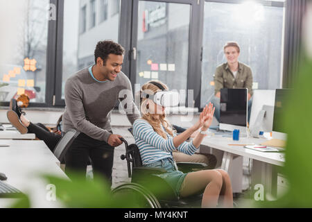Frau im Rollstuhl mit Virtual reality Brillen im modernen Büro Stockfoto