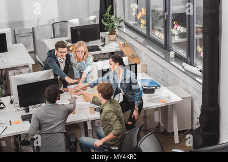 Fröhlich multikulturellen Team bilden der Hände bei modernen Büro Stapel Stockfoto