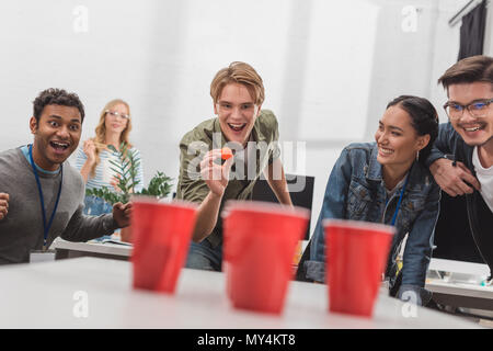 Junge attraktive Menschen spielen Bier pong im modernen Büro nach der Arbeit Stockfoto