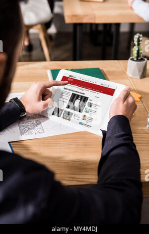 Zugeschnittenes Bild des Geschäftsmannes holding Tablet mit geladenen bbc News Seite Stockfoto