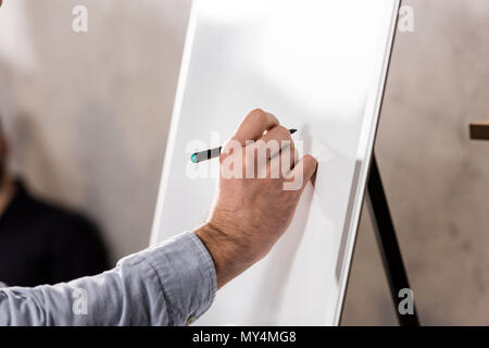 Zugeschnittenes Bild des Geschäftsmannes schreiben etwas auf Flipchart Stockfoto