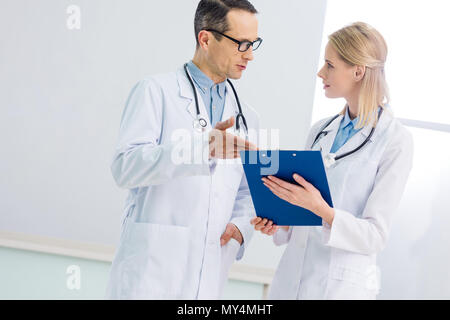 Zwei Ärzte in weißen Kitteln sprechen über Diagnose im Krankenhaus Stockfoto