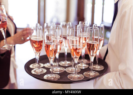 Kellner bedienen die Gäste mit roze Wein aus einer Platte während einer Feier Party Stockfoto