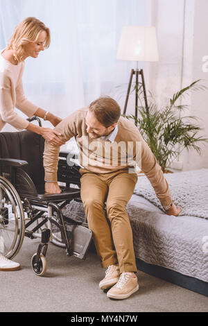 Frau helfen Mann mit Behinderung sitzen auf Rollstuhl Stockfoto