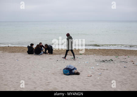VAMA VECHE, Rumänien - Mai 1, 2018: Junge Menschen Ruhe am Strand unter den Trümmerteilen (vor allem leere Flaschen), nach der Party die ganze Nacht, in den frühen Mo Stockfoto