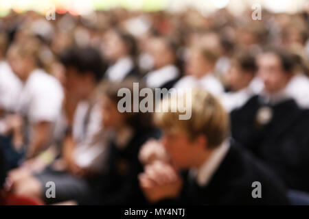 Studenten in Uniform sitzen aufmerksam zuhören an der High School Assembly in dieselbe Richtung zeigen. Schwer für Anonymität und Hintergrund wirkt verschwommen Stockfoto