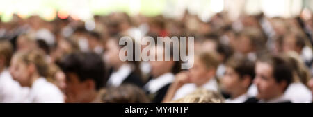 Studenten in Uniform sitzen aufmerksam zuhören an der High School Assembly in dieselbe Richtung zeigen. Schwer für Anonymität und Hintergrund wirkt verschwommen Stockfoto