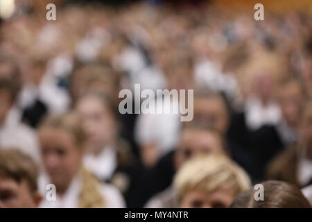 Studenten in Uniform sitzen aufmerksam zuhören an der High School Assembly in dieselbe Richtung zeigen. Schwer für Anonymität und Hintergrund wirkt verschwommen Stockfoto