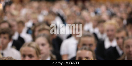 Studenten in Uniform sitzen aufmerksam zuhören an der High School Assembly in dieselbe Richtung zeigen. Schwer für Anonymität und Hintergrund wirkt verschwommen Stockfoto