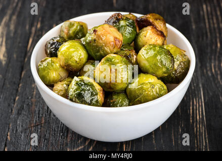 Gebratener Rosenkohl in weißer Keramik Schüssel auf dem Tisch, Nahaufnahme Stockfoto