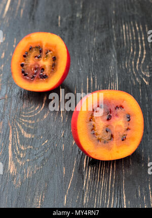 Zwei Hälften von frischem Obst tamarillo auf einen dunklen Tisch Stockfoto