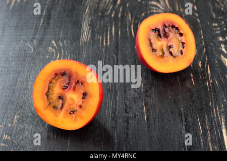 Zwei Hälften von frischem Obst tamarillo auf einen dunklen Tisch closeup Stockfoto